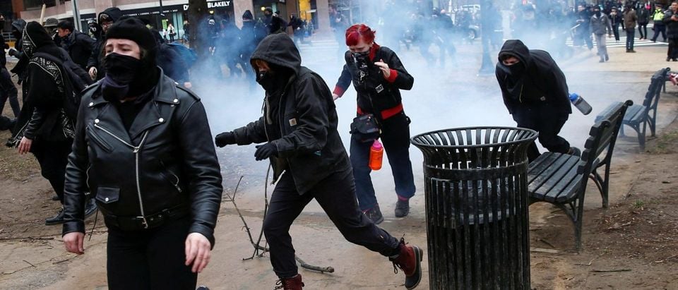 Masked 'Black Bloc' members race after being hit by a stun grenade while protesting against Trump on the sidelines of the inauguration in Washington. REUTERS/Adrees Latif.