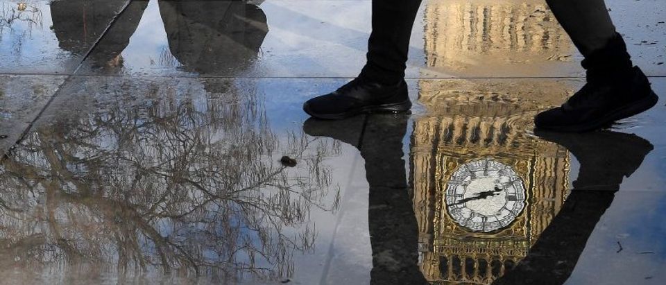 The Elizabeth Tower, commonly known as Big Ben, together with walkers are seen reflected in a puddle in London, Britain