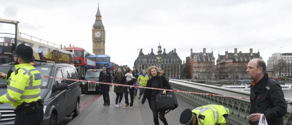 A woman ducks under a police tape after an incident on Westminster Bridge in London