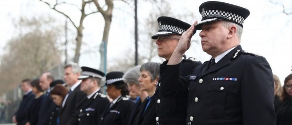 Police officers salute during a minute's silence outside New Scotland Yard. REUTERS/Neil Hall