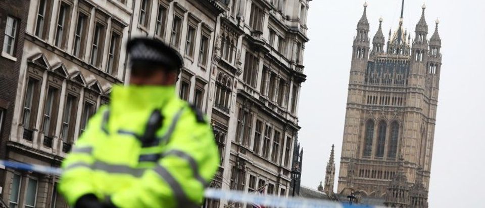 A police officer stands on duty as the union flag flies over Parliament at half-mast the morning after an attack by a man driving a car and weilding a knife left five people dead and dozens injured, in London