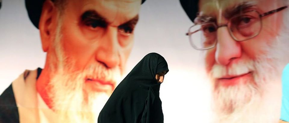 An Iranian woman walks past a giant poster showing supreme leader, Ayatollah Ali Khamenei (R) and the founder of Iran's Islamic Republic, Ayatollah Ruhollah Khomeini (L) during a ceremony marking the 36th anniversary of his return from exile on February 1, 2015 at Khomeini's mausoleum in a suburb of Tehran. (Photo credit: ATTA KENARE/AFP/Getty Images)