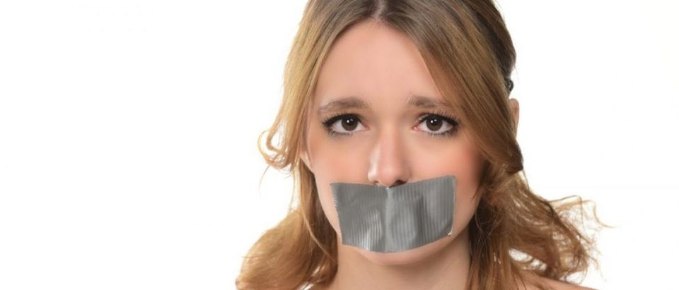 A young woman has tape over her mouth. (Photo: Shutterstock/bobanphotomkd)