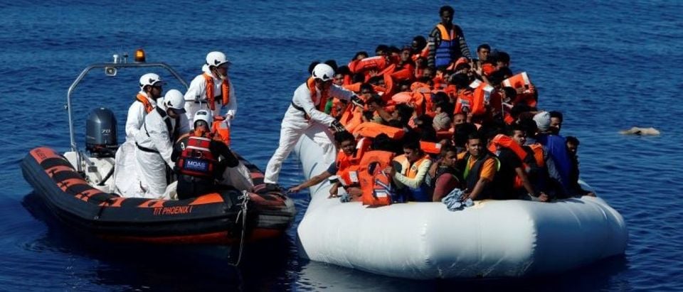 Rescuers from Malta-based NGO Migrant Offshore Aid Station (MOAS) distribute life jackets to migrants on a rubber dinghy in central Mediterranean on international waters off Zuwarah