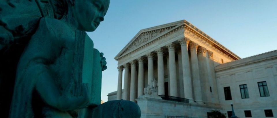 A figure of a child holding an open book decorates a flagpole at the U.S. Supreme Court building in Washington