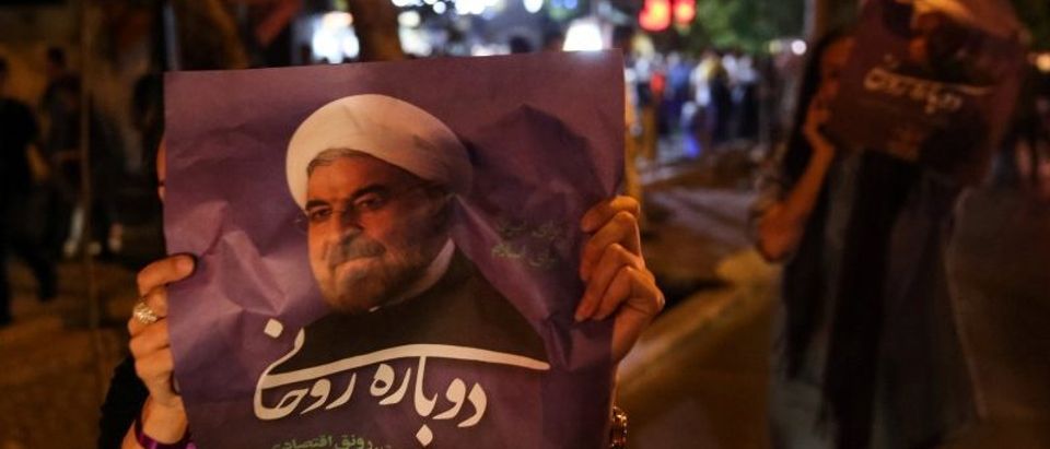 A supporter of Iranian president Hassan Rouhani holds his poster as she celebrates his victory in the presidential election, in Tehran