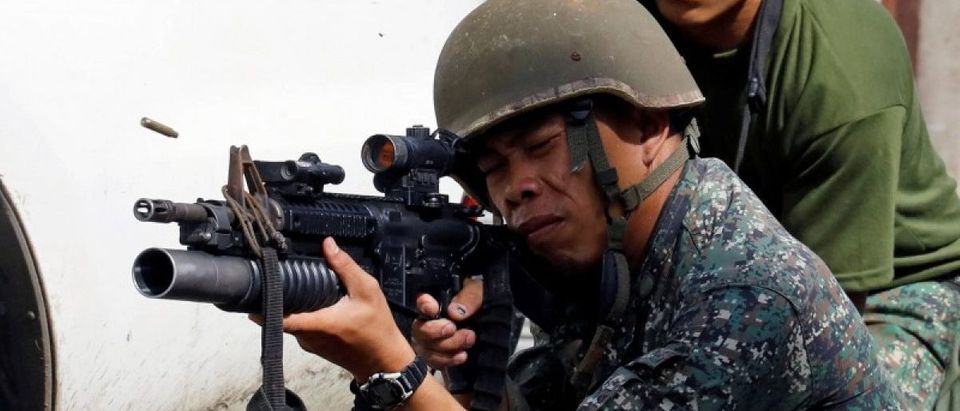 A Philippine Marine fires his weapon towards the stronghold of Maute group in Marawi City