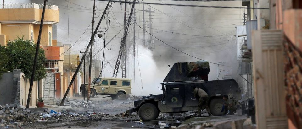 An Iraqi special forces soldier takes cover behind a humvee during an Islamic State fighter car bomb suicide attack in Tahrir neighbourhood of Mosul