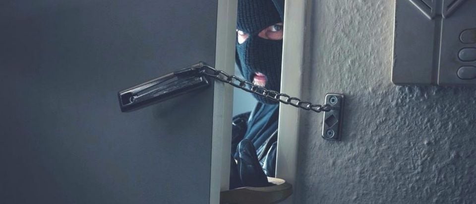 Dangerous masked burglar with crowbar breaking into a victim's home. [Shutterstock - r.classen]