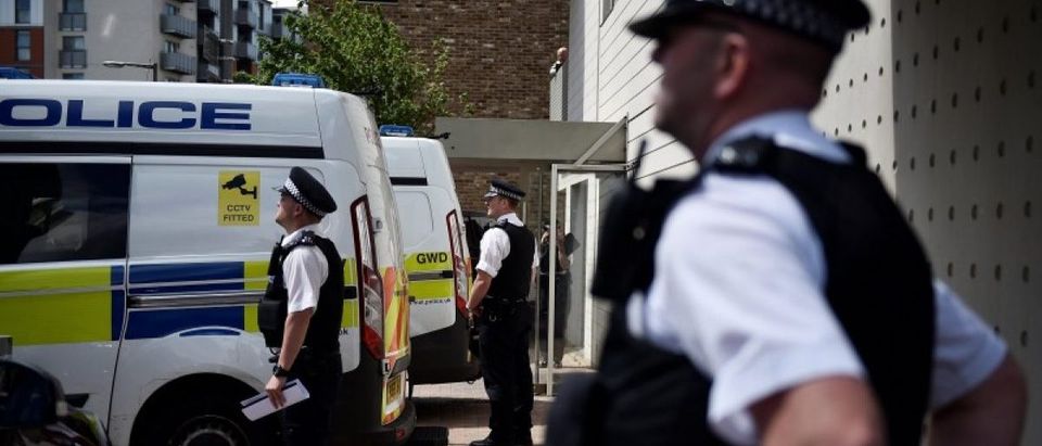 Officers and vehicles stand outside a block of flats that was raided by police in Barking, east London