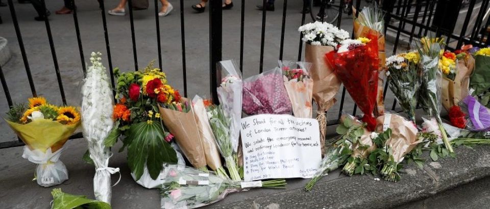 Commuters walk past flowers and messages left outside Monument Underground station next to London Bridge following an attack which left 7 people dead and dozens of injured in central London
