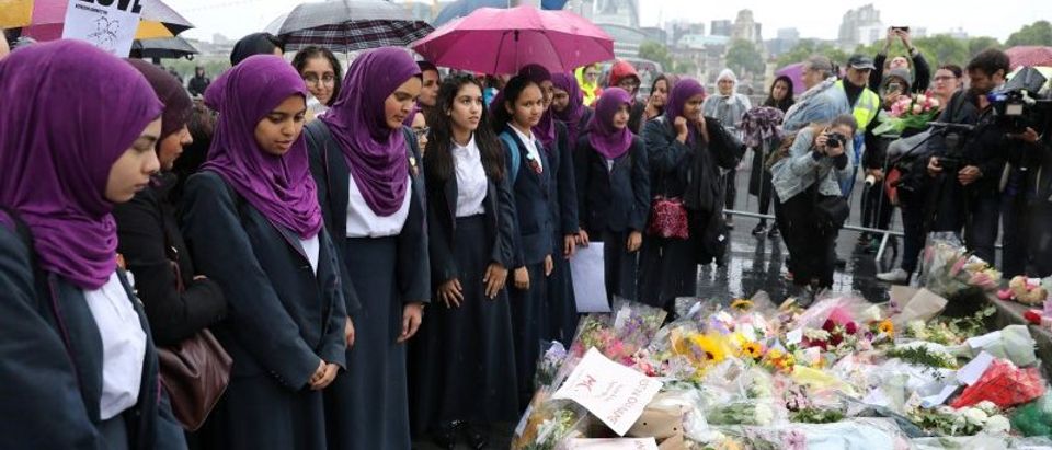 School girls look at floral tributes after a vigil to remember the victims of the attack on London Bridge and Borough Market, at Potters Field Park, in central London