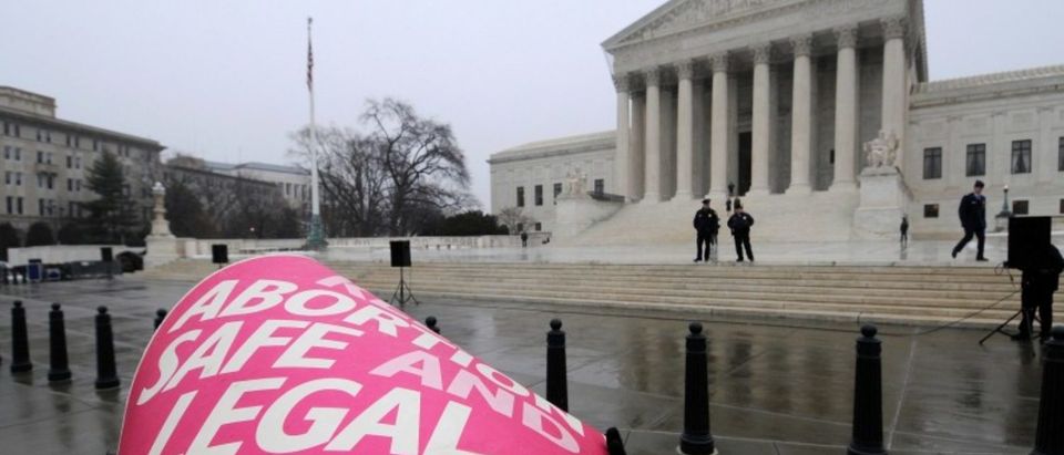 A woman holds a sign in the rain as abortion rights protesters arrive to prepare for a counter protest on the 39th anniversary of the Roe vs Wade decision, in front of the U.S. Supreme Court building