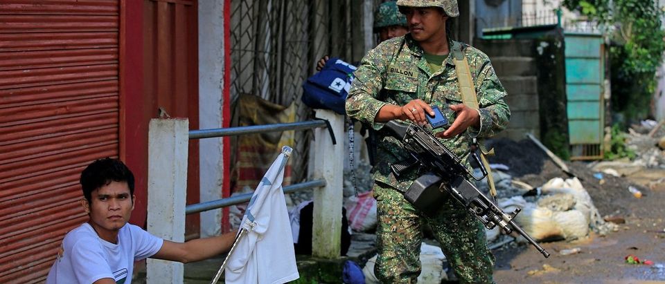 A government soldier looks at a man holding a white flag, who fled his home, as government troops continue their assault on insurgents from the Maute group, who have taken over large parts of the Marawi City