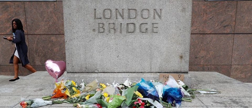 A woman passes flowers left on the south side of London Bridge near Borough Market after an attack left 7 people dead and dozens of injured in London