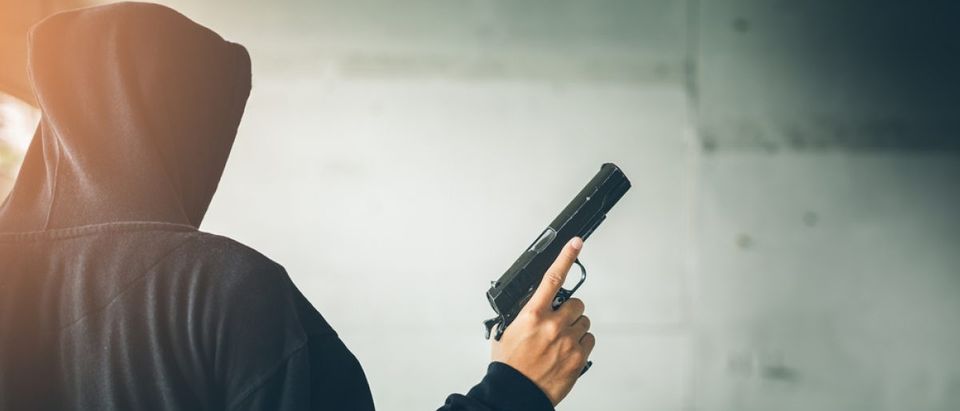 Gang member holds a gun. Source: Chayantorn Tongmorn/Shutterstock