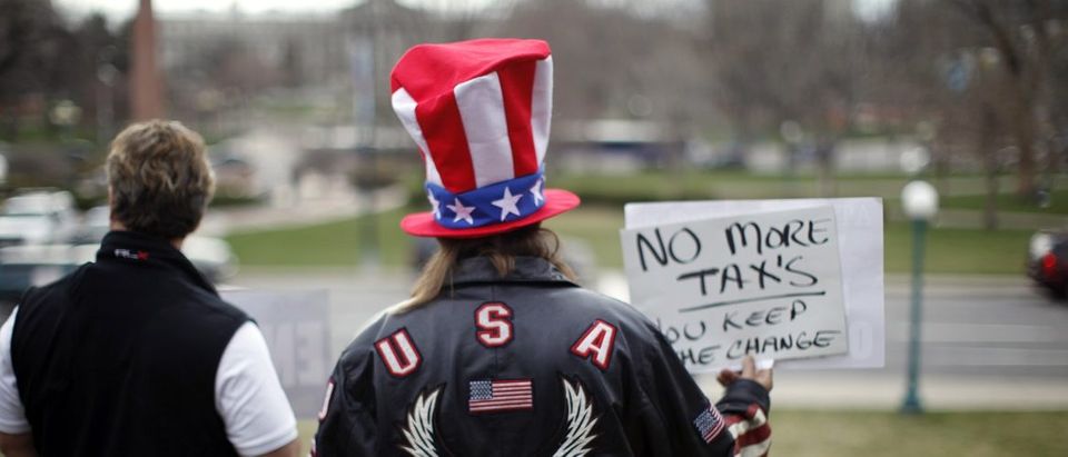 A protester holds up a sign while waiting for the Tea Party Express bus to arrive on the steps of the state capitol in Denver