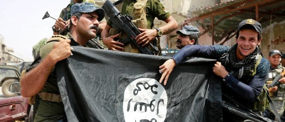 Iraqi Federal Police members hold an Islamic State flag, which they pulled down during fighting between Iraqi forces and Islamic State militants, in the Old City of Mosul