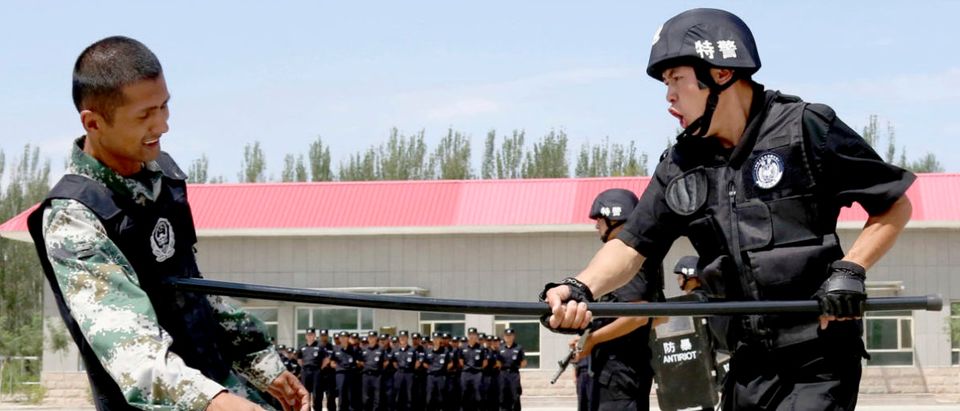 A policeman (R) from Special Weapons and Tactics (SWAT) team fights with a stick against a mock attacker during a graduation performance after training as members of an anti-terrorist patrol team, in Hami, Xinjiang Uighur Autonomous Region June 29, 2014. Picture taken June 29, 2014. REUTERS/China Daily