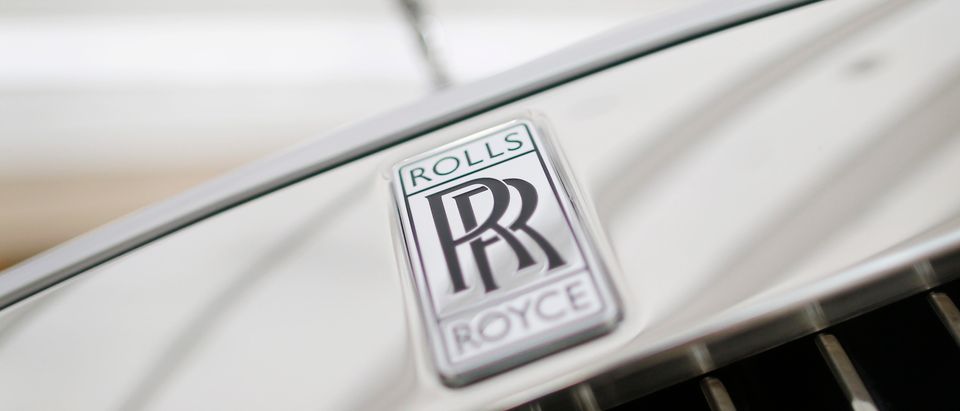 A Rolls-Royce mascot known as 'Spirit of Ecstasy' stands above the brand's logo on the front of a Rolls-Royce Ghost in a showroom in Singapore