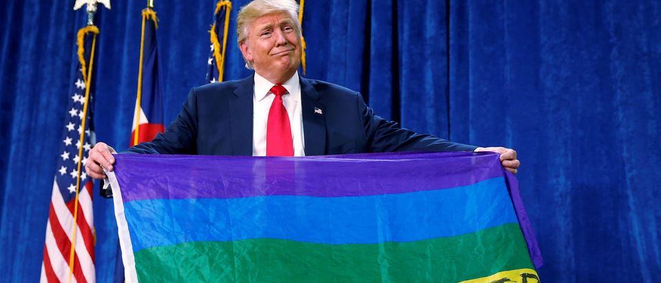 Republican presidential nominee Donald Trump holds up a rainbow flag with "LGBTs for TRUMP" written on it at a campaign rally in Greeley