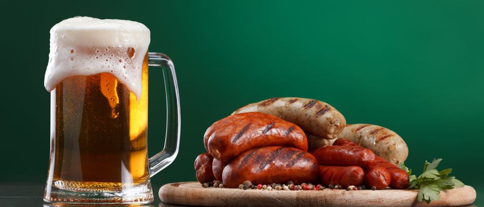 Shutterstock/ Traditional Oktoberfest menu. Beer being poured into a glass with foam, traditional snacks, sausages grilled. Copyspace with green background