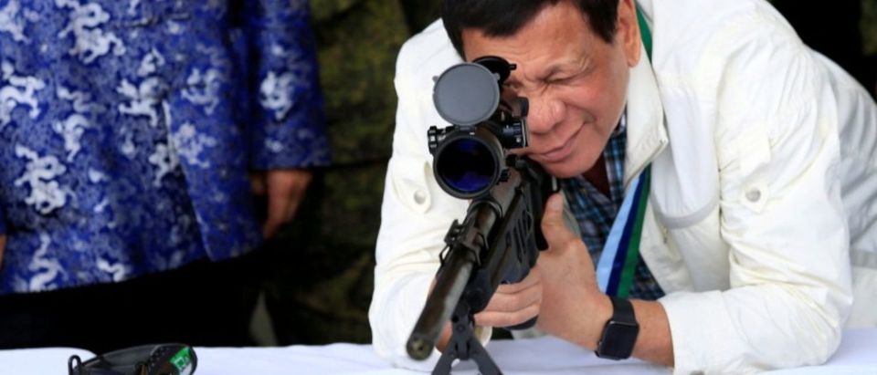 FILE PHOTO - Duterte checks sniper rifle during ceremony at Clark Air Base, near Angeles City