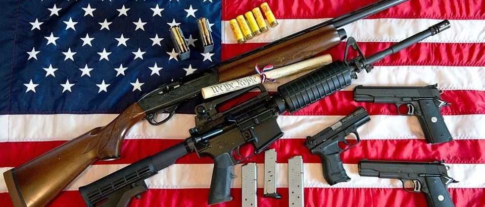 This February 4, 2013 photo illustration in Manassas, Virginia, shows a Remington 20-gauge semi-automatic shotgun, a Colt AR-15 semi-automatic rifle, a Colt .45 semi-auto handgun, a Walther PK380 semi-auto handgun and various ammunition clips with a copy of the US Constitution on top of the American flag. US President Barack Obama Monday heaped pressure on Congress for action "soon" on curbing gun violence. Obama made a pragmatic case for legislation on the contentious issue, arguing that just because political leaders could not save every life, they should at least try to save some victims of rampant gun crime. AFP PHOTO/Karen BLEIER (Photo credit should read KAREN BLEIER/AFP/Getty Images)
