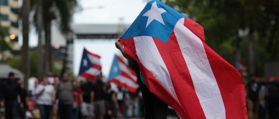 A person carries a Puerto Rican national flag during a protest against the government's austerity measures as Puerto Rico faces a deadline on Monday to restructure its $70 billion debt load or open itself up to lawsuits from creditors, in San Juan