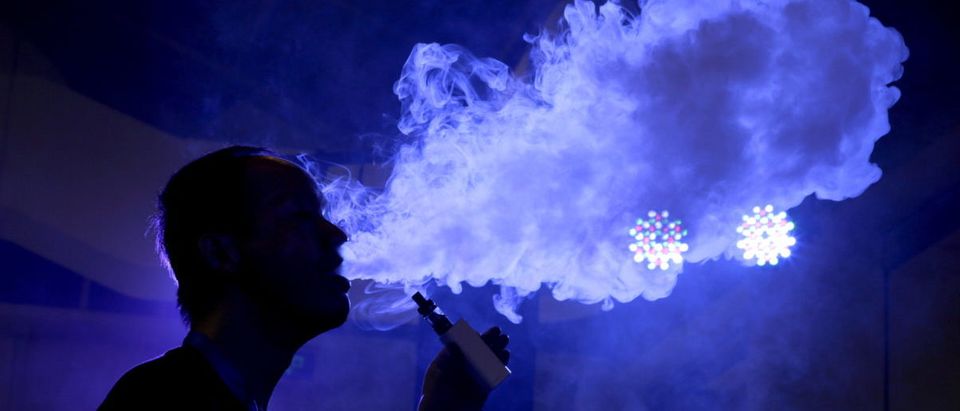 An exhibitor staff member uses an electronic cigarette at VAPE CHINA EXPO in Beijing