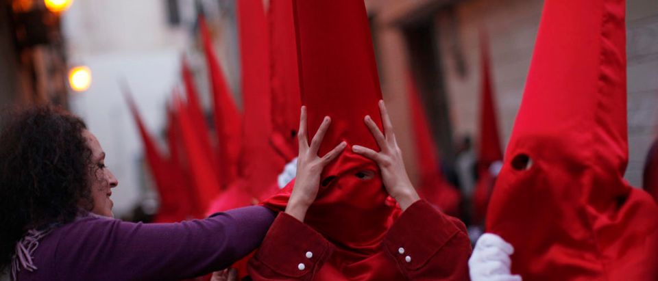 A woman adjusts a "Capirote" hat on a penitent as he takes part in the Sangre brotherhood procession during Holy Week in Malaga, southern Spain April 4, 2012. Hundreds of processions take place around the clock in Spain during Holy Week, drawing thousands of visitors. REUTERS/Jon Nazca (SPAIN - Tags: RELIGION SOCIETY TPX IMAGES OF THE DAY) - GM1E8450IT301
