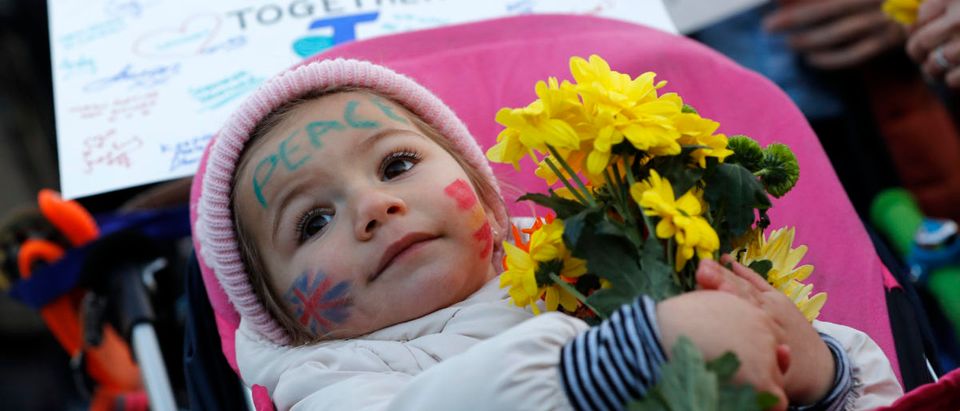 A baby holds a bunch of flowers at a vigil in Trafalgar Square the day after an attack, in London, Britain March 23, 2017. REUTERS/Darren Staples