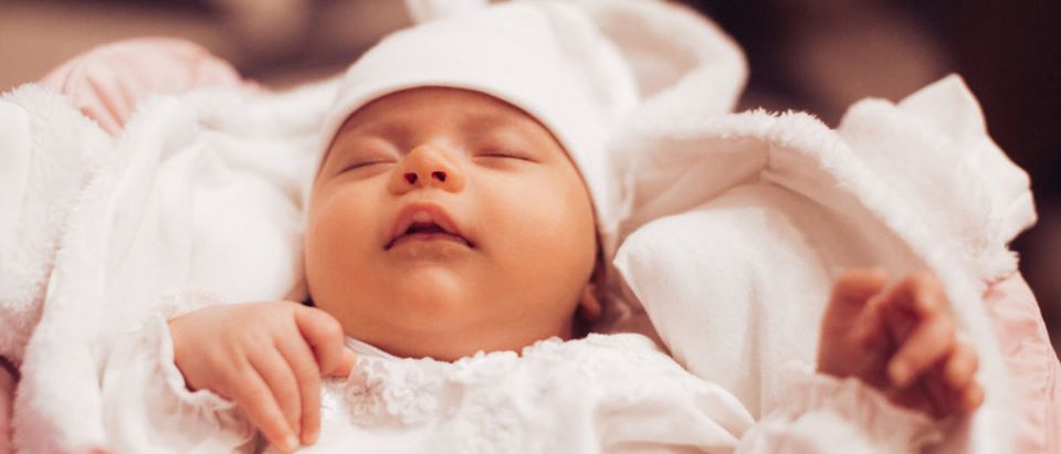 A newborn baby dressed in white clothes sleeps in the cradle. (Photo: shutterstock/pyrozhenka) | Think Tank, Docs To Encourage Abortion