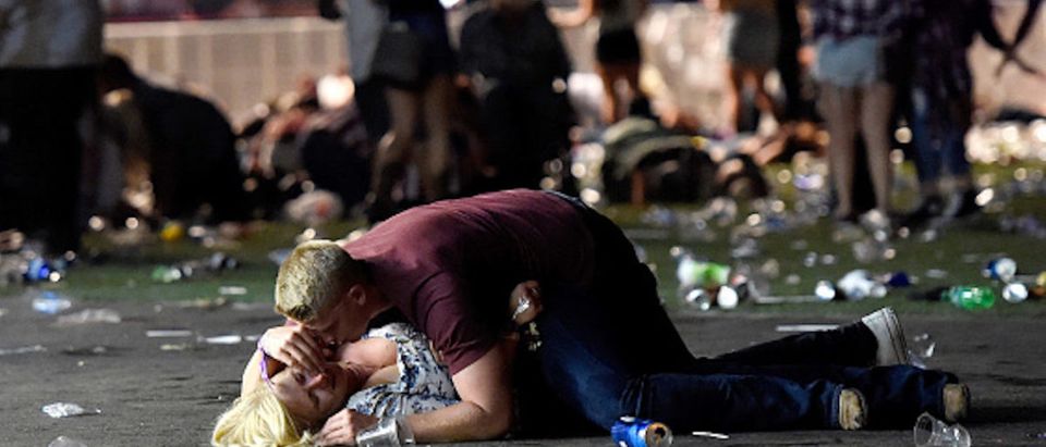 LAS VEGAS, NV - OCTOBER 01: A man lays on top of a woman as others flee the Route 91 Harvest country music festival grounds after a active shooter was reported on October 1, 2017 in Las Vegas, Nevada. A gunman has opened fire on a music festival in Las Vegas, leaving at least 2 people dead. Police have confirmed that one suspect has been shot. The investigation is ongoing. (Photo by David Becker/Getty Images)
