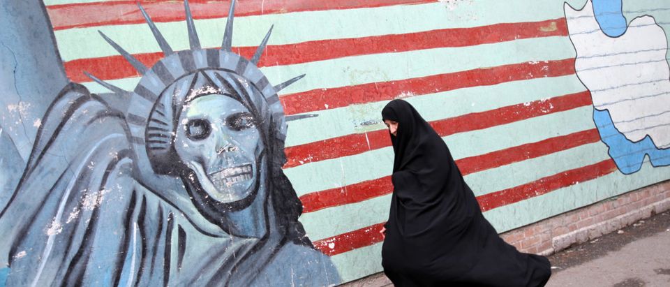 An Iranian woman walks past an anti-US m