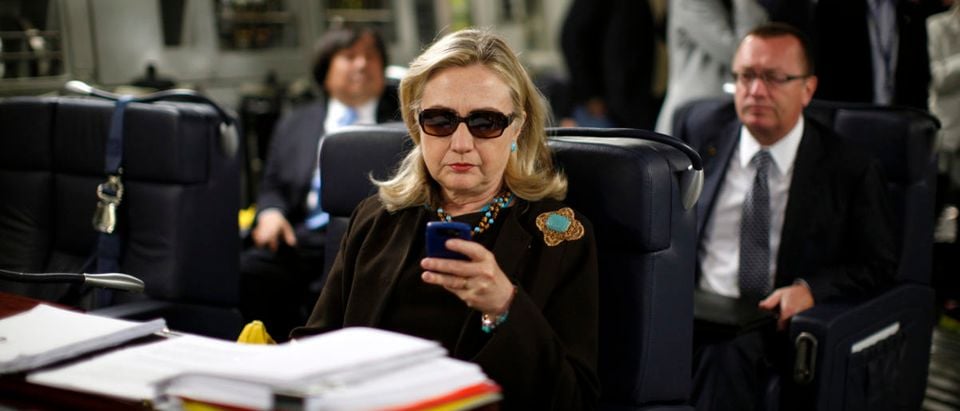 Former Secretary of State Hillary Clinton checks her PDA, Libya October 18, 2011. REUTERS/Kevin Lamarque