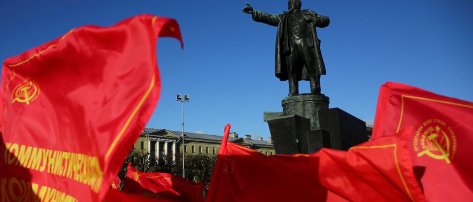 Flags flutter in front of a monument to Soviet state founder Vladimir Lenin during a rally held by Russian Communist Party supporters to mark the Red October revolution's centenary in St. Petersburg, Russia November 7, 2017. REUTERS/Anton Vaganov