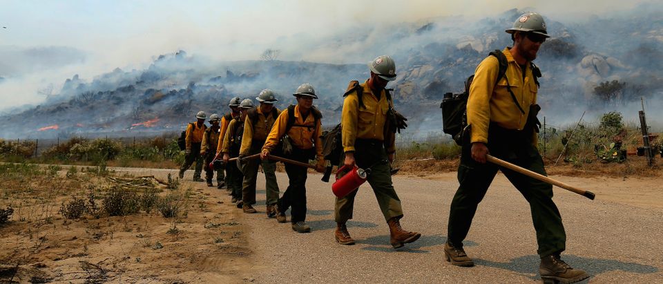 U.S. Forest Service firefighters walk to their truck after battling a wildfire near Potrero