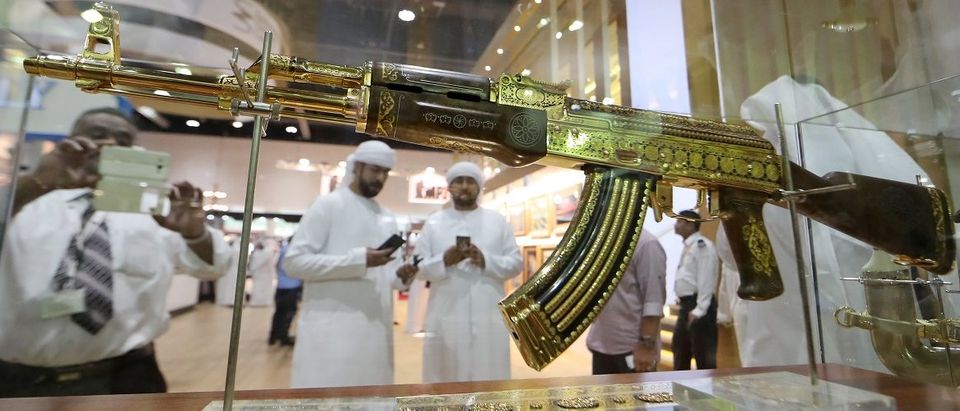 A picture taken on September 14, 2017 shows Emirati men using their cell-phones to take pictutres of an ornamented gold-plated Kalashnikov AK-47 assault rifle on display at the Abu Dhabi International Hunting and Equestrian exhibition (ADIHEX) in the UAE capital. Karim Sahib/AFP/Getty Images.