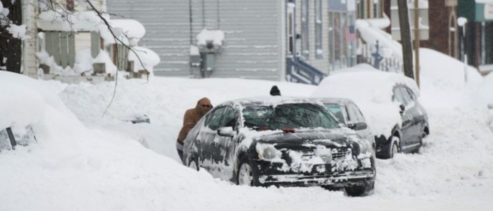 People help dig out a car from a parking spot after two days of record-breaking snowfall in Erie