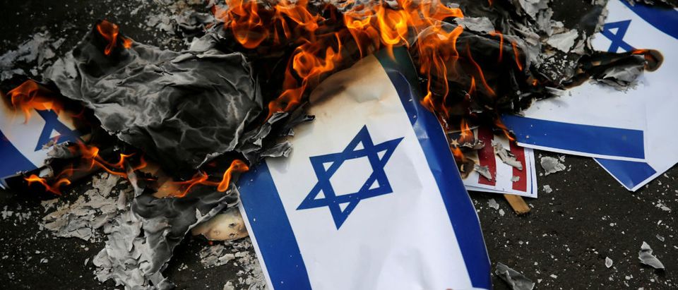 A participant burns an Israeli flag mockup during a protest to condemn Washington's decision to recognize Jerusalem as Israel's capital, outside the U.S. embassy in Jakarta