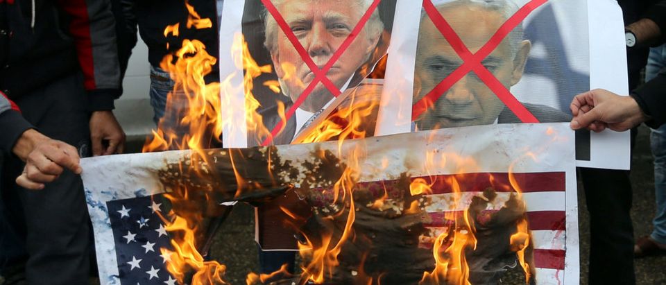 Palestinians burn posters depicting Israeli Prime Minister Benjamin Netanyahu and U.S. President Donald Trump during a protest against the U.S. intention to move its embassy to Jerusalem and to recognize the city of Jerusalem as the capital of Israel, in Rafah in the southern Gaza Strip December 6, 2017. REUTERS/Ibraheem Abu Mustafa