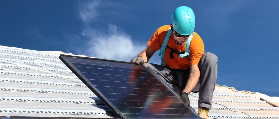 A Man installs alternative energy photovoltaic solar panels on roof. (Photo: Federico Rostagno/Shutterstock)