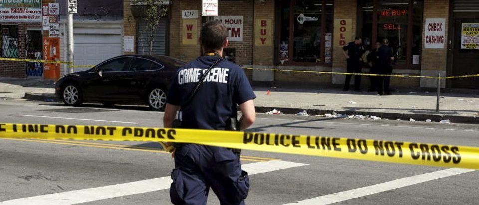 A police crime scene technician heads in to document evidence at the scene of a shooting at the intersection of West North Avenue and Druid Hill Avenue in West Baltimore, Maryland May 30, 2015. Local media have reported more than 35 murders in the city of Baltimore since the April rioting over the death of 25-year-old resident Freddie Gray and shootings continue regularly in his West Baltimore neighborhood. REUTERS/Jim Bourg