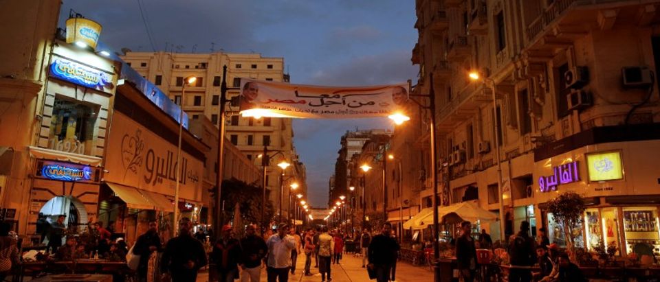 Egyptians walk in a street under a poster of President Abdel Fattah al-Sisi displayed for the campaign “Together for the best of Egypt" that calls for al-Sisi to run in the next year's presidential election in the capital of Cairo