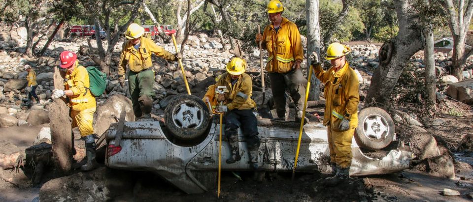 Rescue workers search cars for missing persons after a mudslide in Montecito, California,