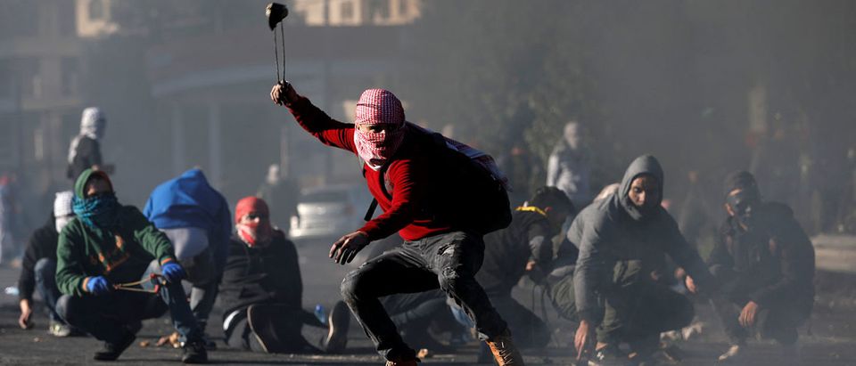 A Palestinian protester uses a sling to hurl stones towards Israeli troops during clashes near the Jewish settlement of Beit El, near the West Bank city of Ramallah