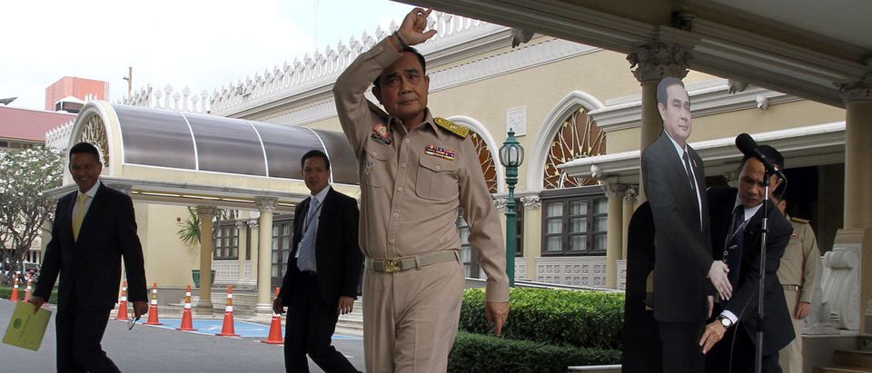 Thailand's Prime Minster Prayuth Chan-ocha speaks to reporters next to a cardboard cut-out of himself at the government house in Bangkok