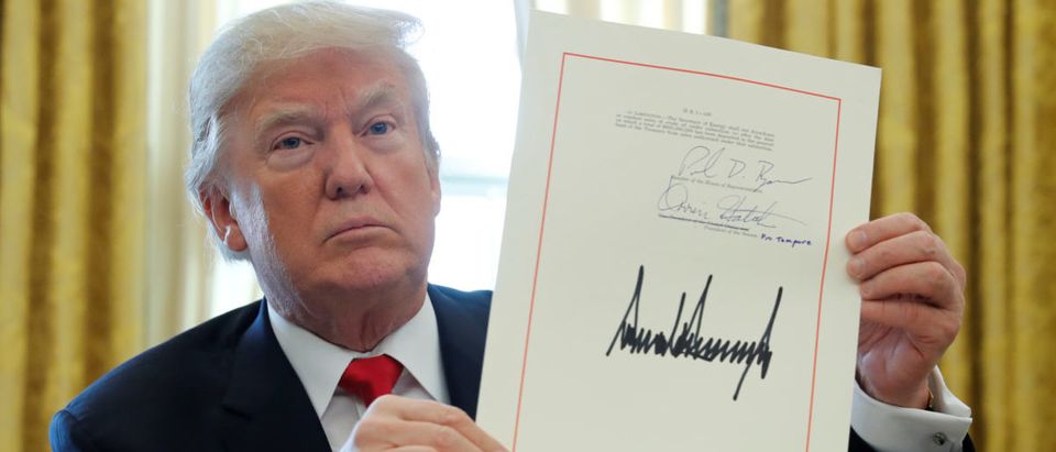 FILE PHOTO: U.S. President Donald Trump displays his signature after signing the $1.5 trillion tax overhaul plan in the Oval Office of the White House in Washington, U.S., December 22, 2017. REUTERS/Jonathan Ernst
