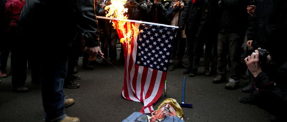 Protesters burn the American flag and an effigy of U.S. President Donald Trump in front of the U.S. embassy in Montreal